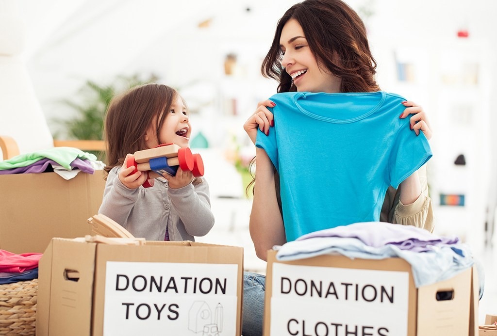 Mother and daughter preparing toys and clothes to donate for charity.