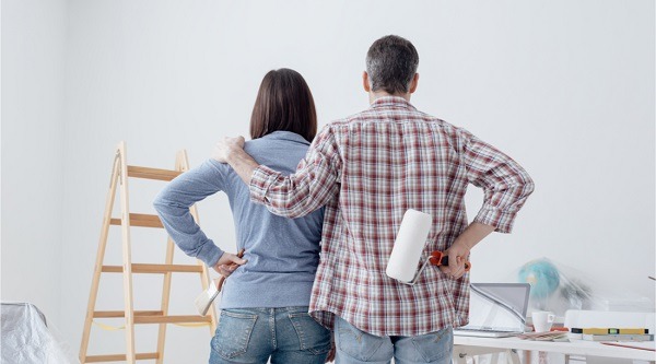 A couple standing next to each other while painting a room