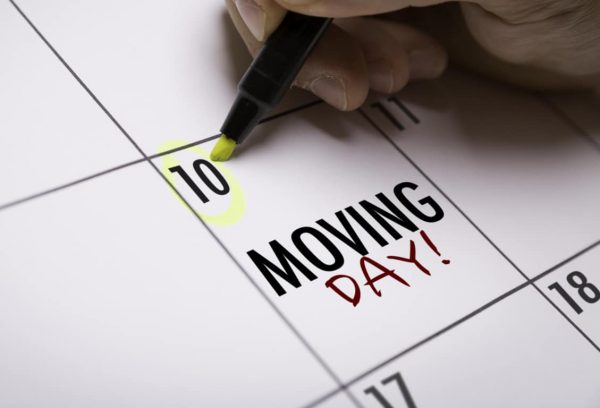 a hand using a yellow highlighter to mark a calendar for moving day